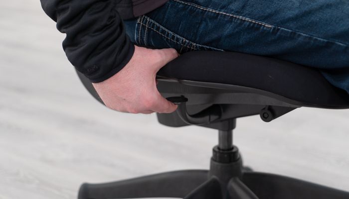 Hand on height adjustment lever under seat pad